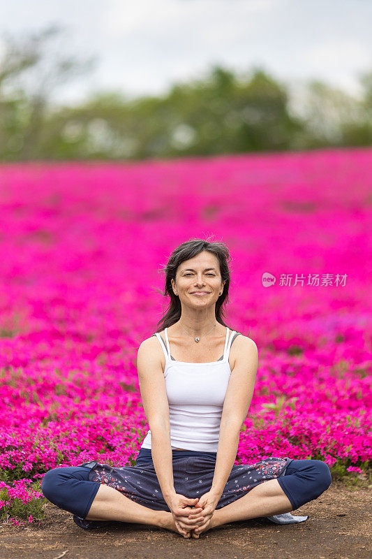 一位女士在粉红色的花田前沉思，享受户外的乐趣