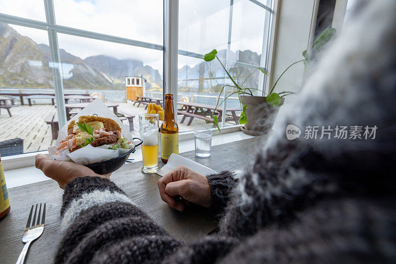 一名男子在当地的海鲜餐厅吃鱼三明治，他的两只手拿着食物