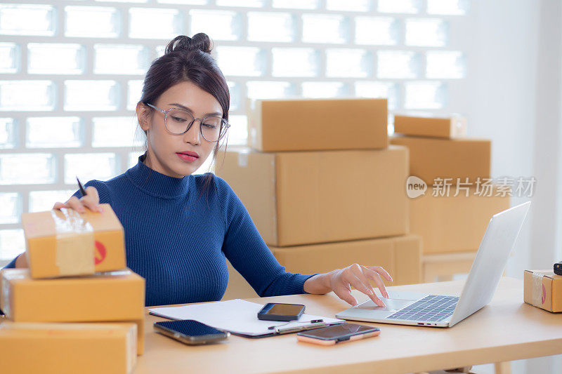 年轻的亚洲女性在网上销售送货服务，而女性在家里的笔记本电脑上查找信息，在网上发货，自由职业者做小企业或中小企业和零售。