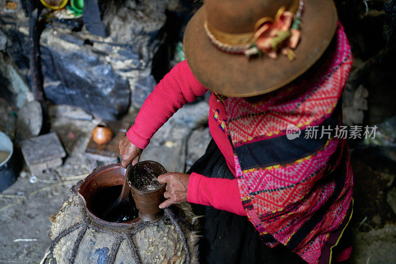 一名来自克丘亚克罗族的妇女将一种来自安第斯山脉的神圣而典型的饮料chica倒入一个粘土玻璃杯中。