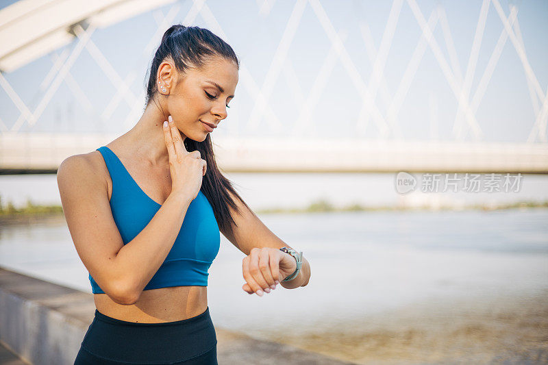 一位年轻的健身女性在脖子上检查自己的脉搏。