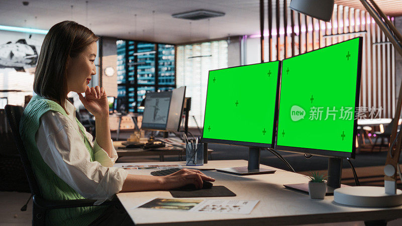 亚洲女游戏设计师使用桌面电脑绿屏Chromakey显示，设计角色在3D建模软件的生存视频游戏。在游戏开发办公室工作的女性