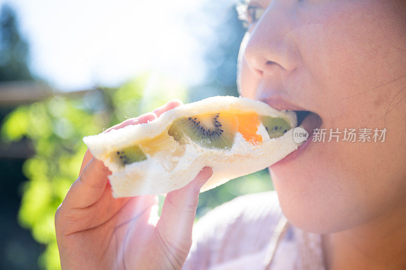 一位女士在一家日本便利店吃了一口水果三明治