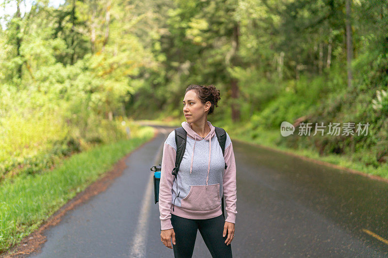 年轻的少数民族妇女走在路上，背着一个背包