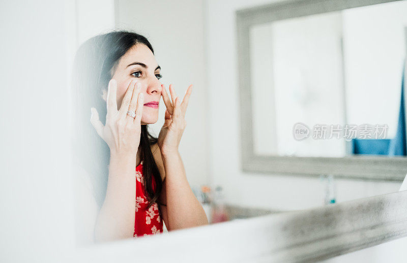 迷人的女人在她的三十多岁在家里的浴室化妆