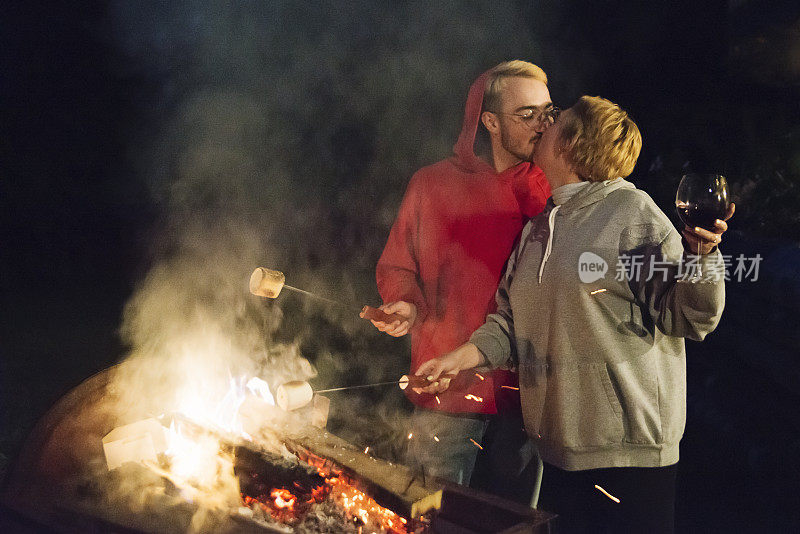 千禧一代夫妇晚上在户外的火上烤棉花糖。
