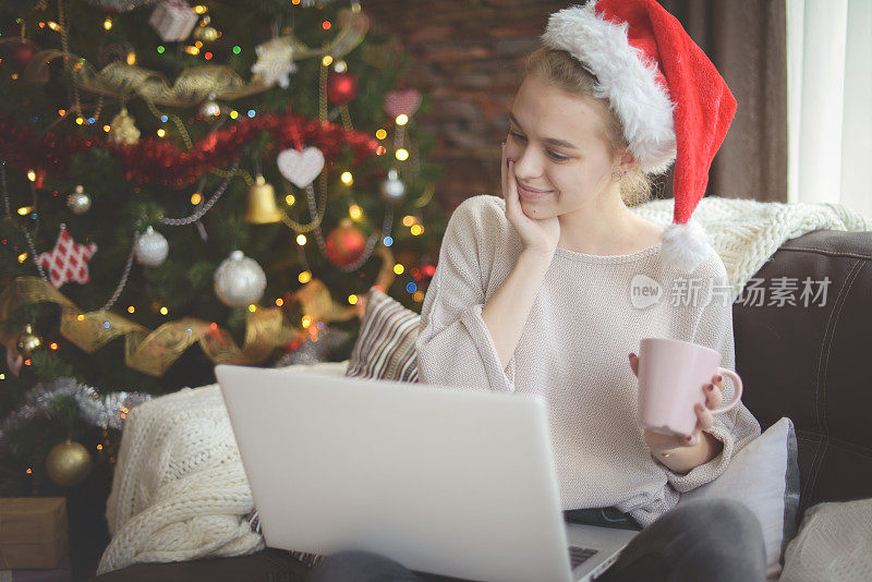 年轻女子在圣诞节室内与笔记本电脑(网上约会)