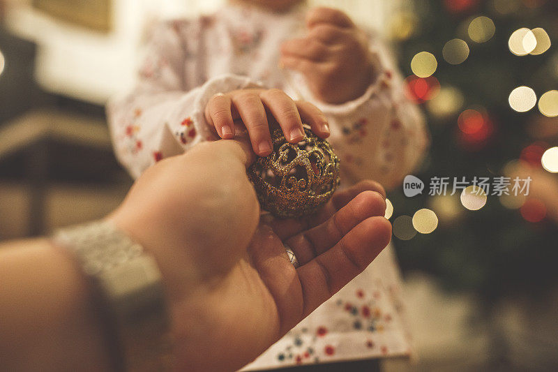 一个男人给一个小女孩一个圣诞装饰品挂在树上
