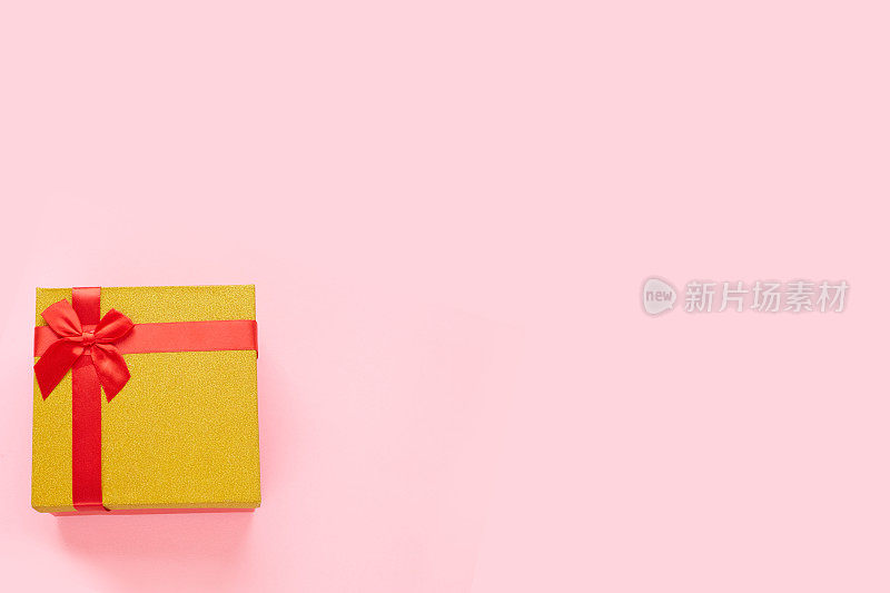 金色盒子，粉红色背景的礼物，圣诞礼物，情人节或妇女节的礼物