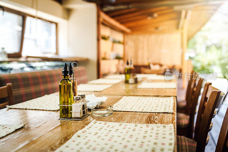 木制餐桌，上面放着一瓶油和一瓶醋。餐馆里舒适的气氛。意大利风格的餐厅。