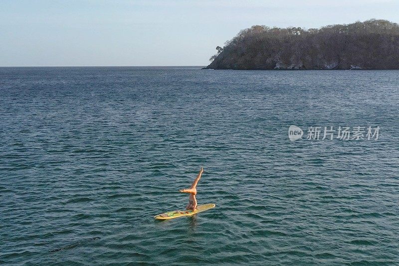 年轻女子在早晨用桨板做瑜伽