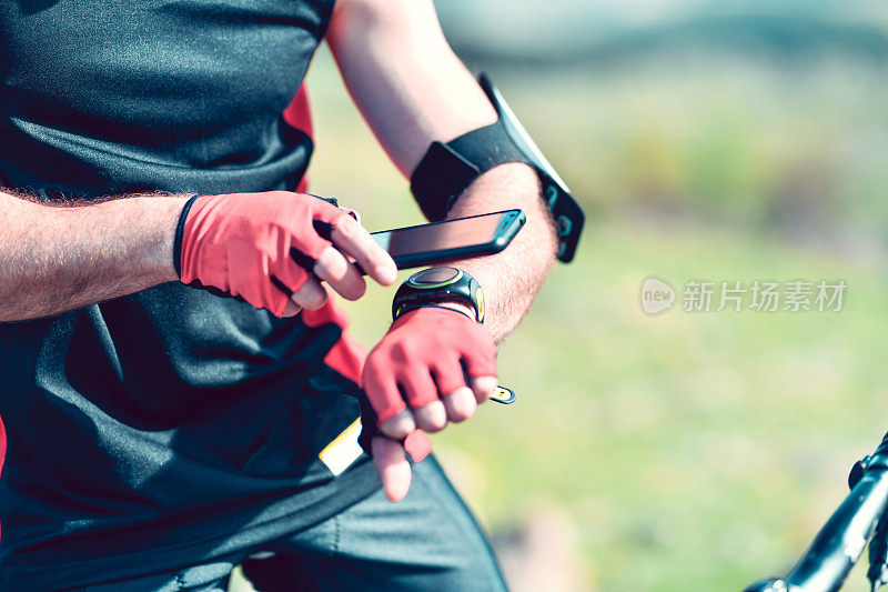 男性自行车手在骑行探险中连接智能手表和智能手机