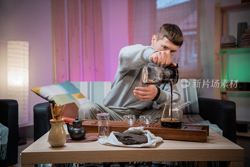 一位年轻人被介绍到中国饮茶文化。在家冲泡香喷喷的生茶。将沸水倒在茶叶上