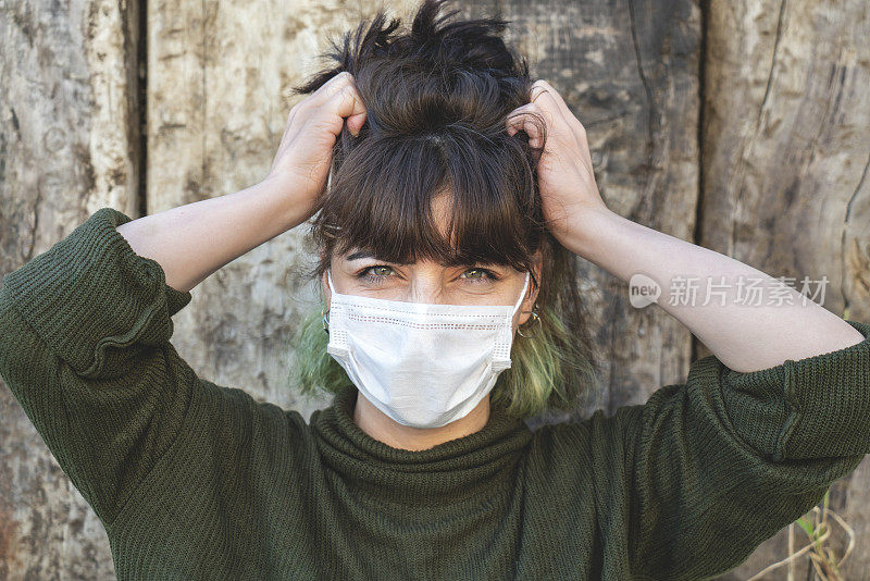 惊恐的年轻女子戴着防护面罩站在木制背景前