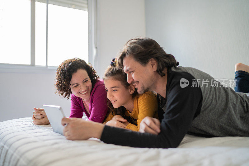 家人在家里的床上用电子平板电脑看东西