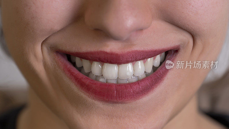 女性牙齿健康微笑的特写镜头。女性微笑的特写。她有健康的牙齿。她在嘴唇上涂了红色的口红。