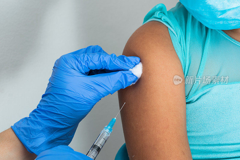 棕色女孩手臂注射后，儿童护士用棉絮擦拭血液。医生正在注射疫苗预防covid-19。流感疫苗。医学概念，健康和流行病。