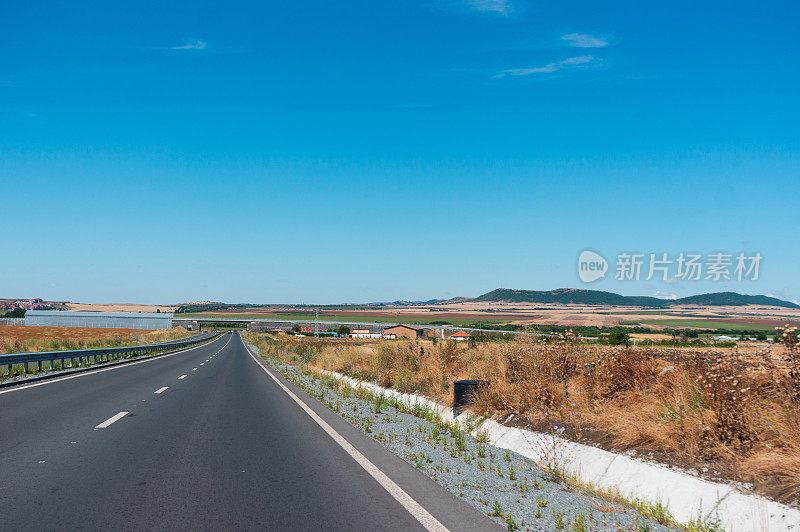 在高速公路上开车经过田野。彩色照片