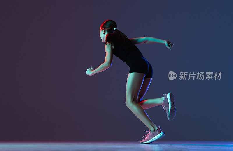 女孩肖像，职业运动员，跑步训练孤立的梯度蓝色紫色背景在霓虹灯