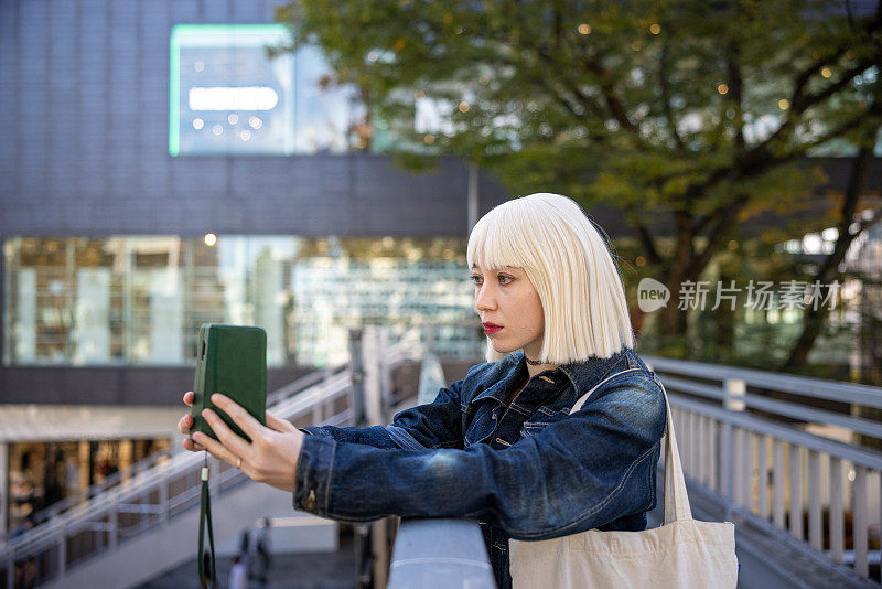 戴着铂金假发的年轻女子在人行天桥上自拍