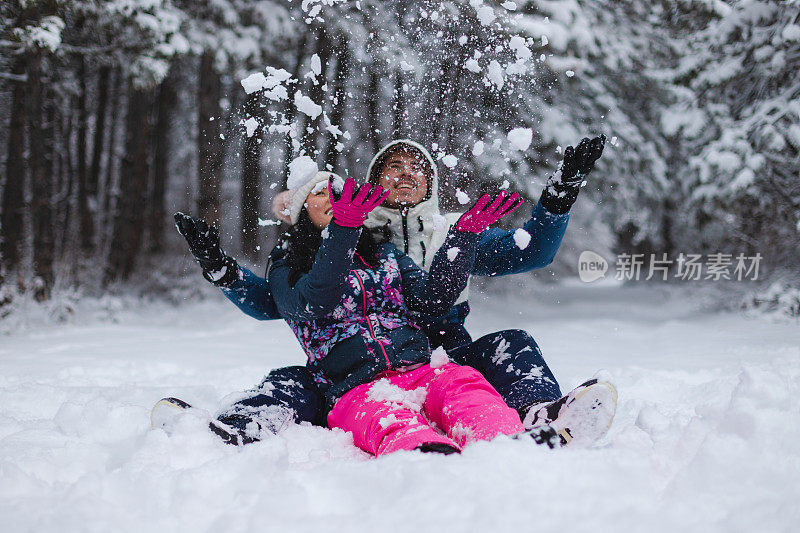 年轻美丽而浪漫的情侣在雪中嬉戏，把雪抛向空中