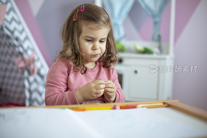 小女孩在她粉红色的房间里用蜡笔画画