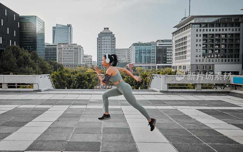 年轻的西班牙混血女性戴着耳机听音乐，在城市外面跑步。锻炼对你的健康和幸福有好处