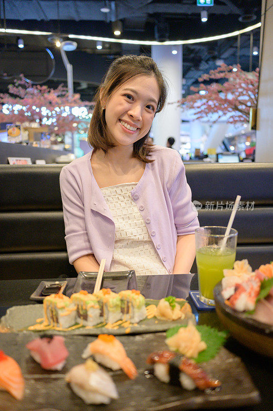 亚洲泰国中国商业妇女吃牛油果寿司和新鲜的沙士米高级设置在餐厅筷子