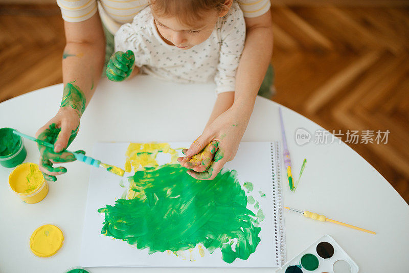 匿名妇女和儿童在家用颜料制作手印