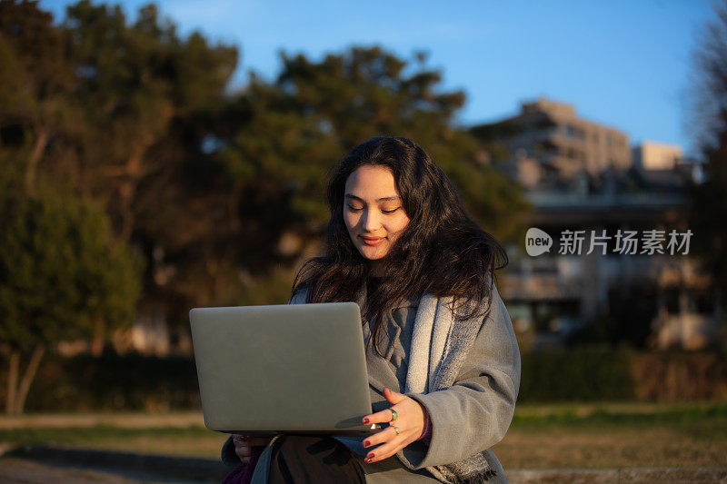 年轻的学生女孩正在外面学习。