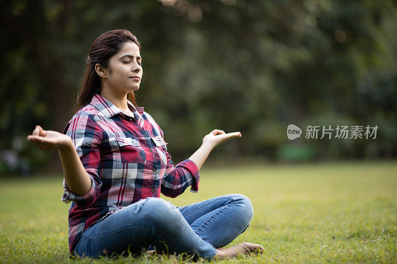 年轻女子在公园冥想。库存图片