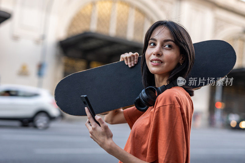 一个年轻的西班牙女人滑着滑板走在街上