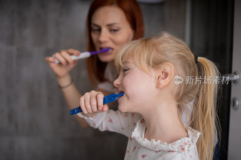 快乐的中年母亲和小女儿正在一起刷牙