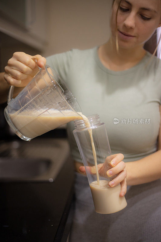 年轻女子在厨房准备运动饮料。