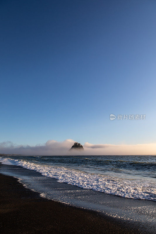 海浪滚进岩石海滩低潮站在强大的大岩层背景重低云蓝天