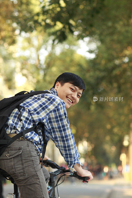 亚洲大学生在校园里骑自行车