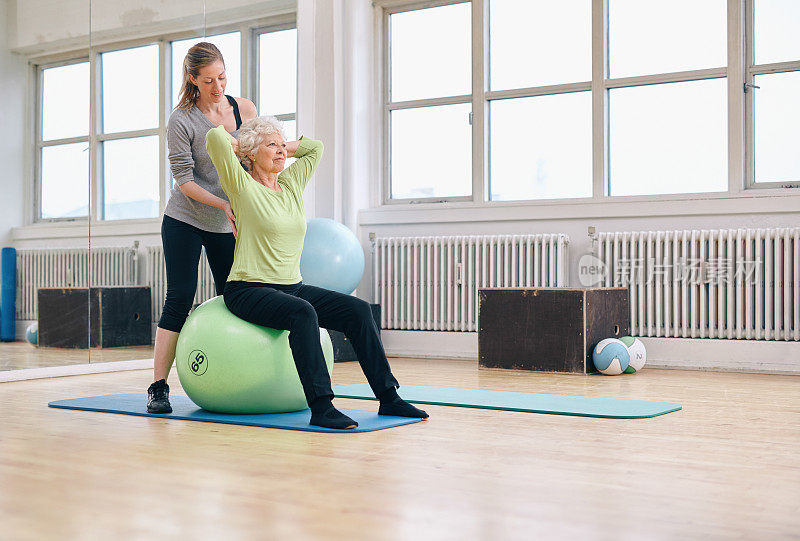 在健身房帮助老年女性锻炼的女教练