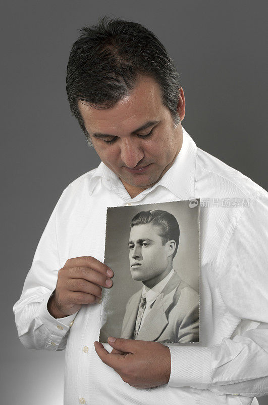 一个男人拿着他父亲的旧照片