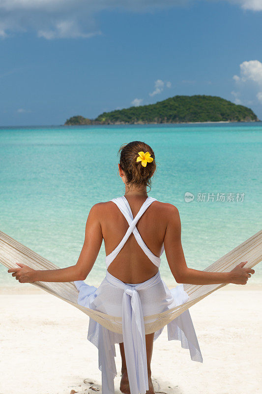 在加勒比海的海滩上，一个面目全非的女人坐在吊床上