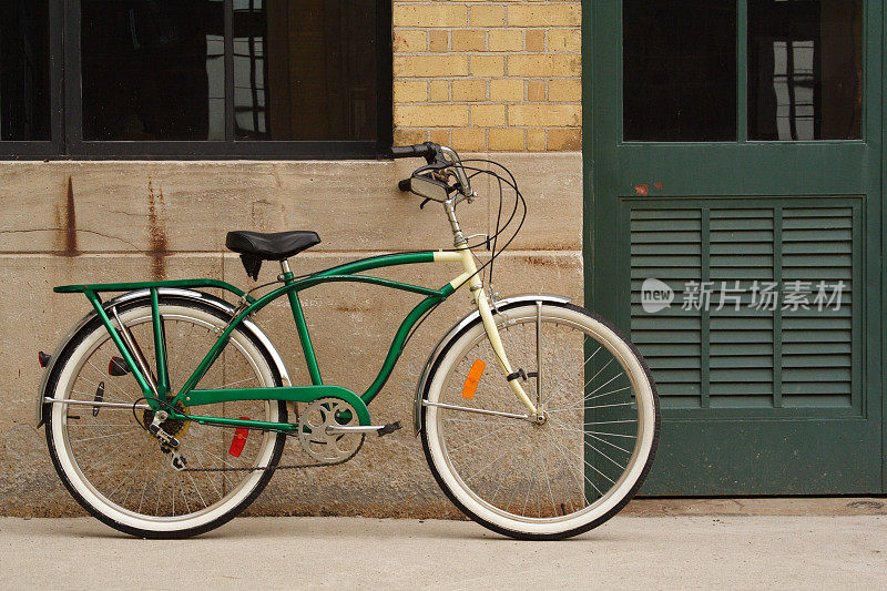 靠在砖墙、水泥墙和绿色门上的老式自行车