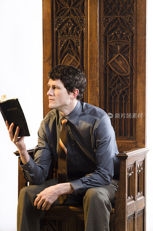 坐在华丽椅子上读圣经的年轻人