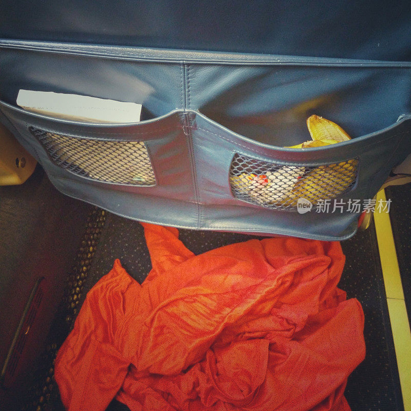 肮脏的飞机乘客座位口袋，垃圾，香蕉皮，毯子