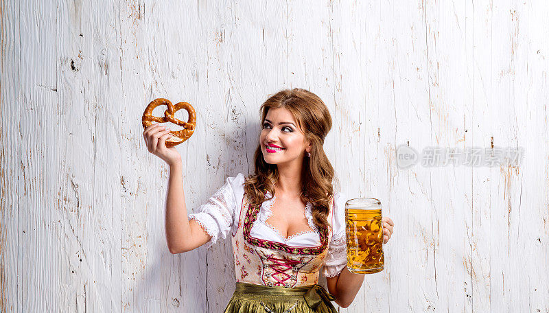 身着传统巴伐利亚连衣裙的女子，手里拿着啤酒和椒盐卷饼