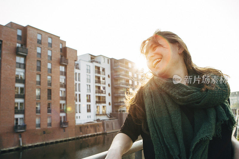 城市生活:笑着的女人靠在栏杆上，背光