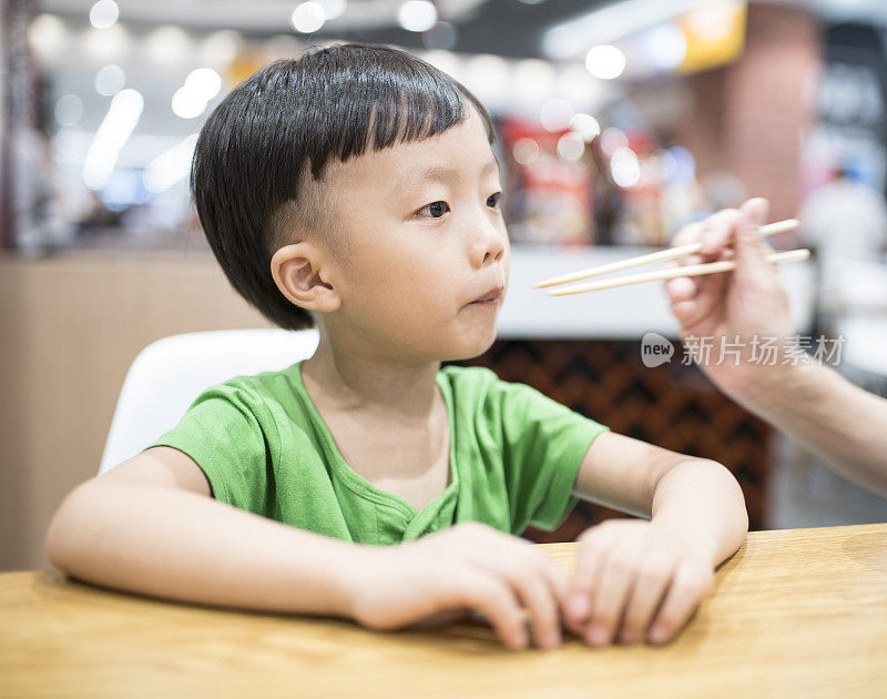 快乐的亚洲孩子用筷子吃美味的面条