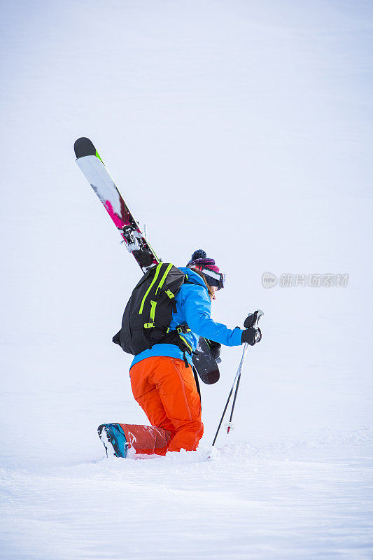 女滑雪者在深粉中登山。