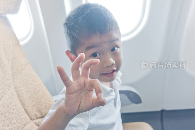 小男孩在飞机上显示OK的标志
