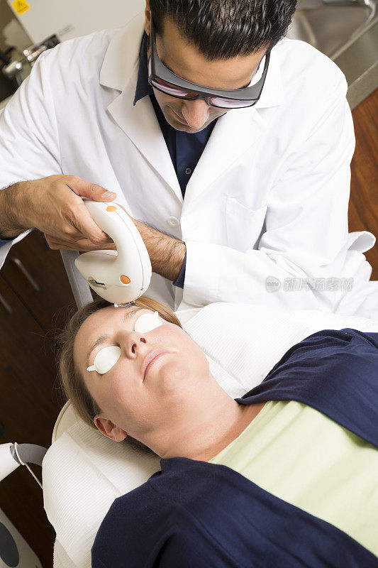 医生执行激光皮肤平滑的过程对一个中年妇女