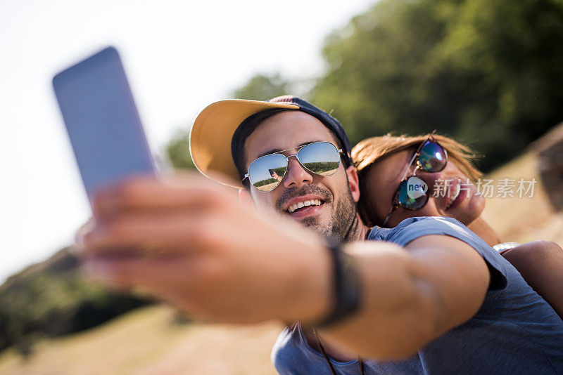 年轻的幸福夫妇在户外用手机自拍。