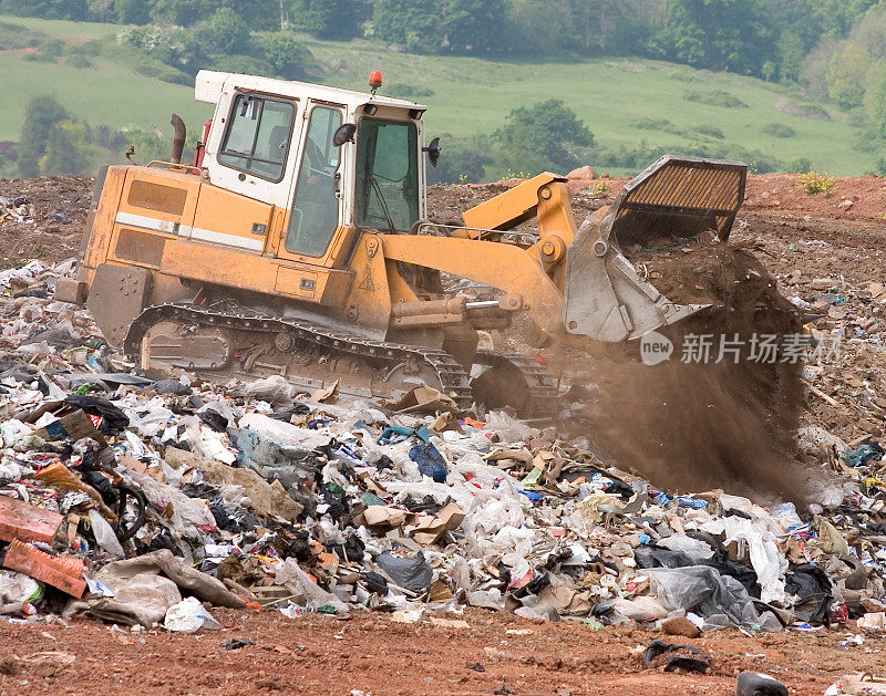垃圾填埋场用推土机在垃圾上倾倒泥土